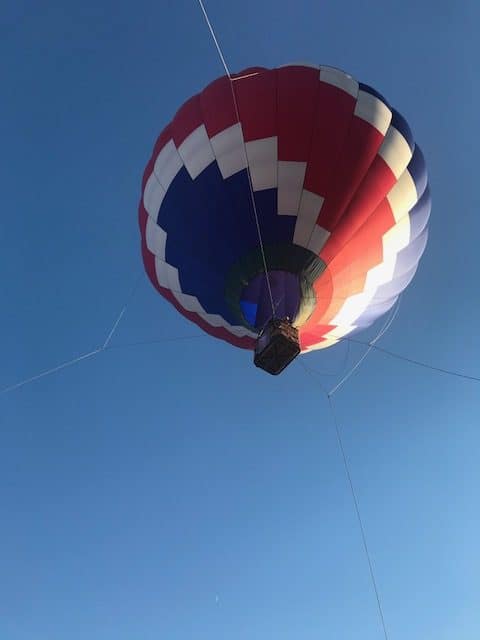 Looking up towards a Hot Air Balloon up in the sky.