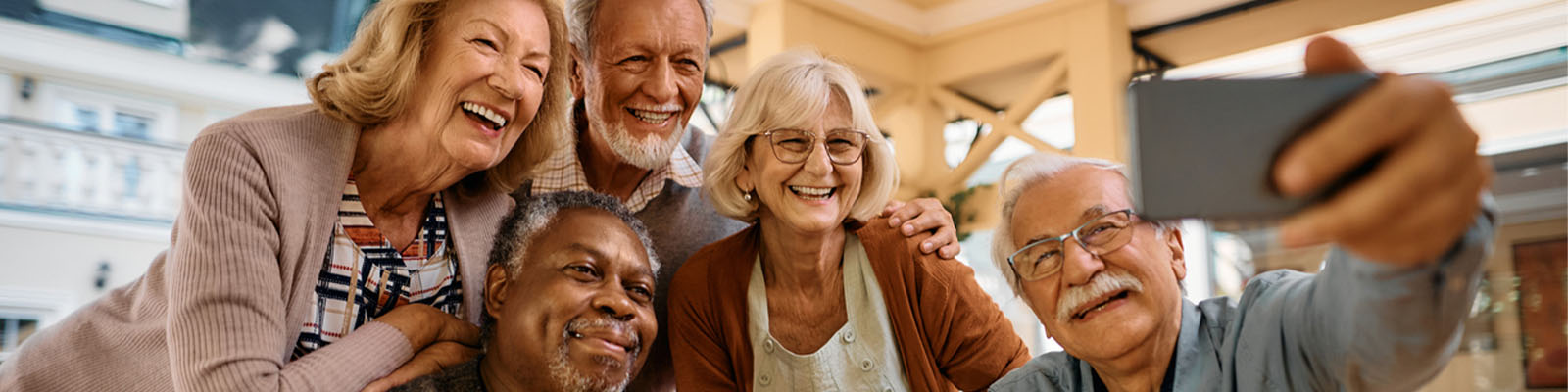 A group of senior men and women smiling while taking a selfie picture on a smartphone